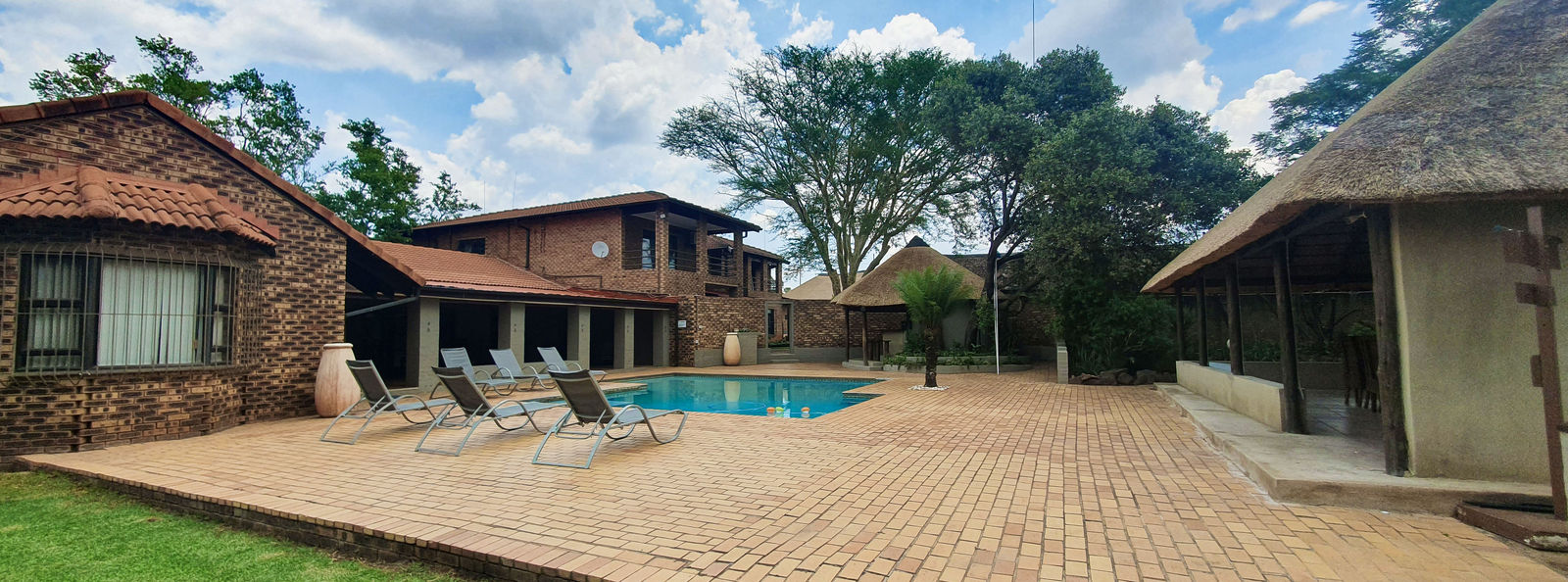 The swimming pool surrounded by thatched lodge buildings.