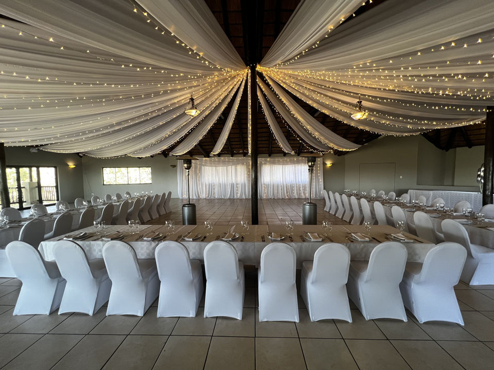 A wedding reception room with draped ceilings and dressed tables.
